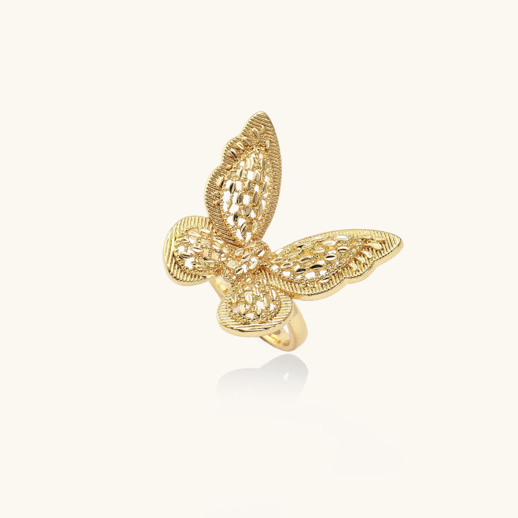 Intricate gold-plated butterfly ring with filigree cutout wings and adjustable band on white background.