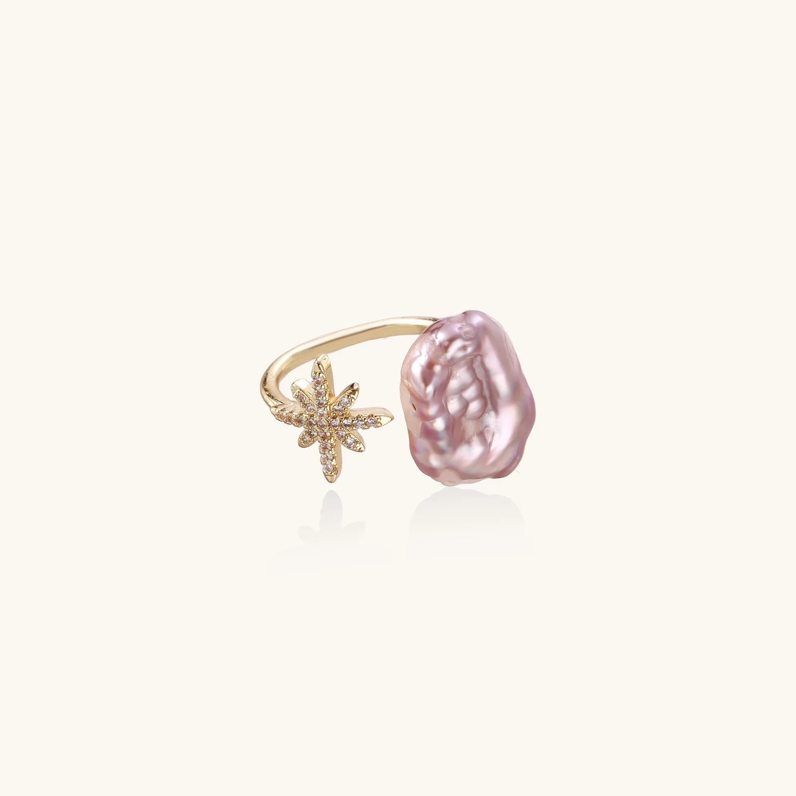 Adjustable gold ring with pink baroque freshwater pearl and crystal-studded star charm on white background