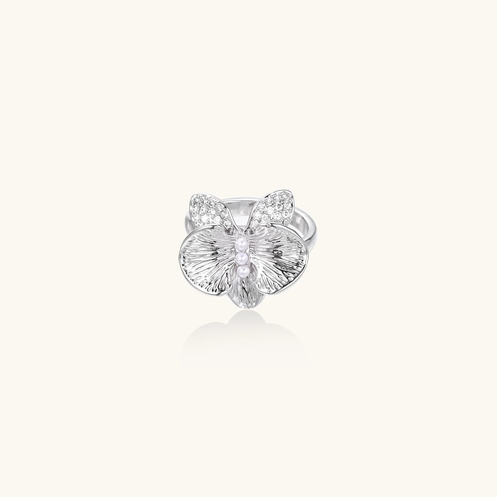 Silver-toned orchid ring with textured petals, pearl center accents, and sparkling zirconia stones on white background.