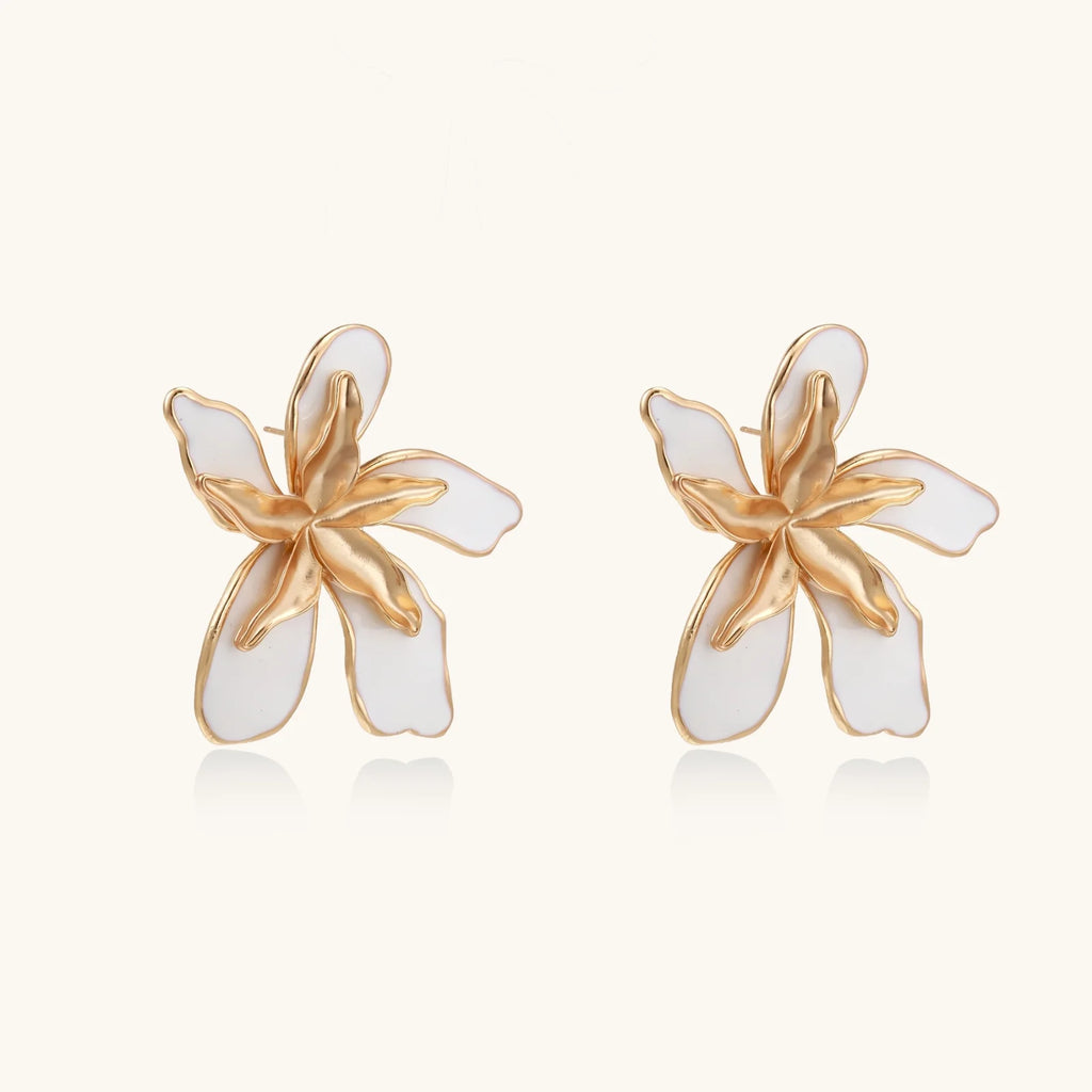 White enamel tropical flower earrings with sculptural gold-plated center and organic petal design on cream background