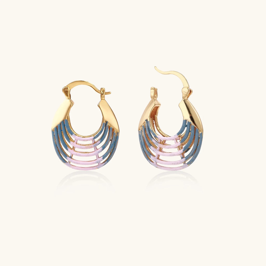 Gold hoop earrings with gradient blue-to-pink enamel in ribbed fan design on beige background