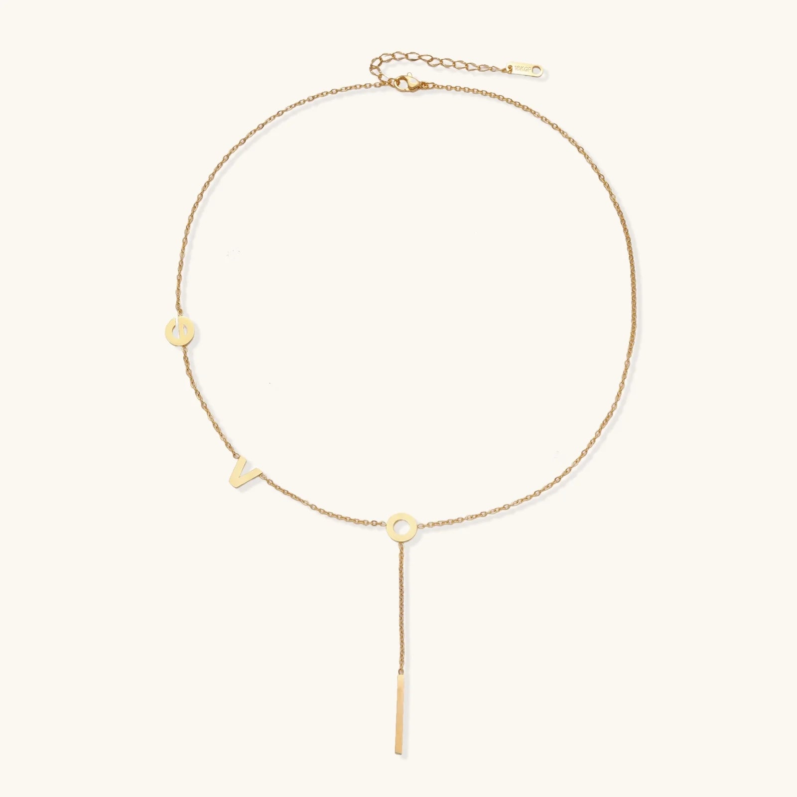 Gold Y-shaped necklace with L-O-V-E letter charms and vertical bar pendant on delicate chain against cream background