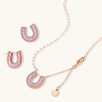 Sparkling horseshoe-shaped jewelry set with AAA cubic zirconia in gold-plated and white gold finishes on cream background.