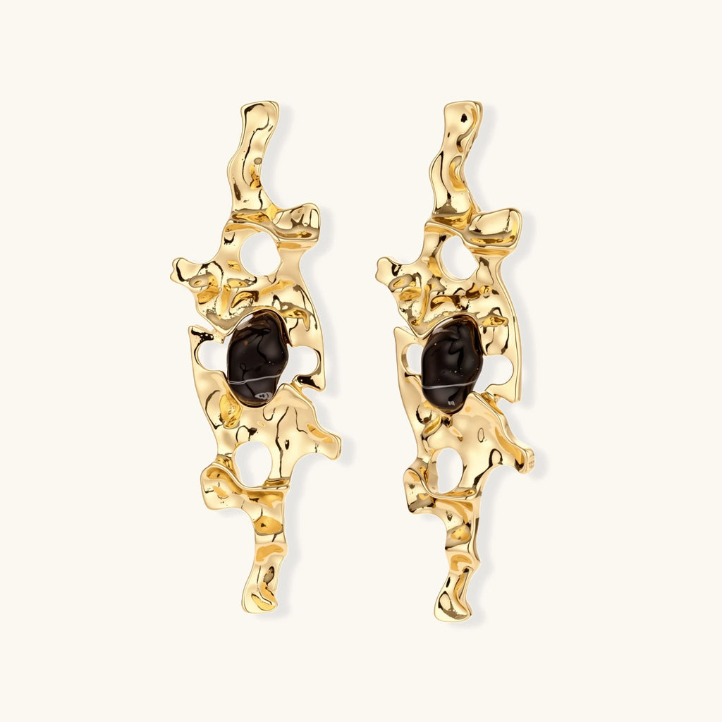 Elongated sculptural earrings with organic openwork design in eco-zinc alloy and dark resin accents on white background.