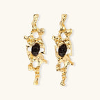 Elongated sculptural earrings with organic openwork design in eco-zinc alloy and dark resin accents on white background.