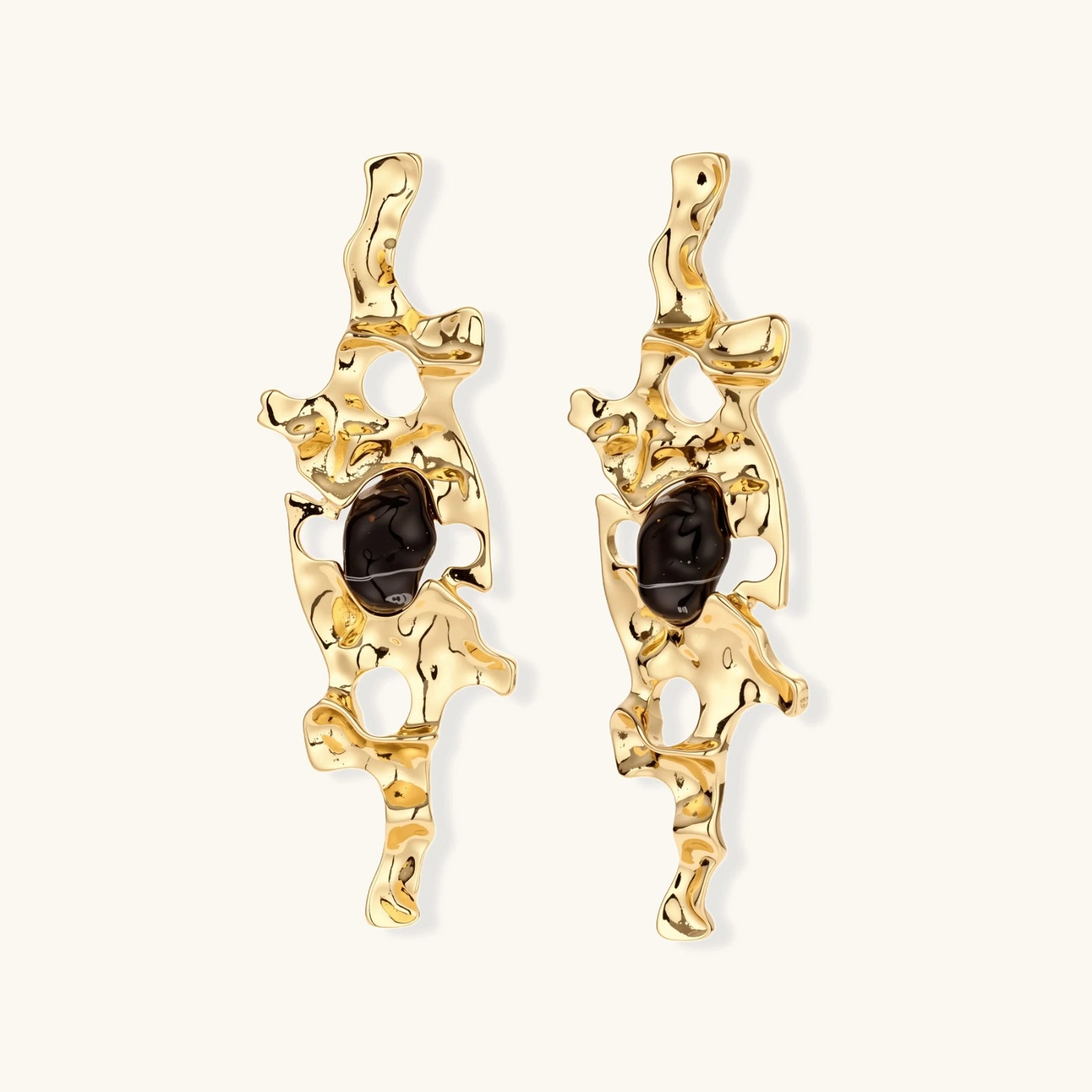 Elongated sculptural earrings with organic openwork design in eco-zinc alloy and dark resin accents on white background.
