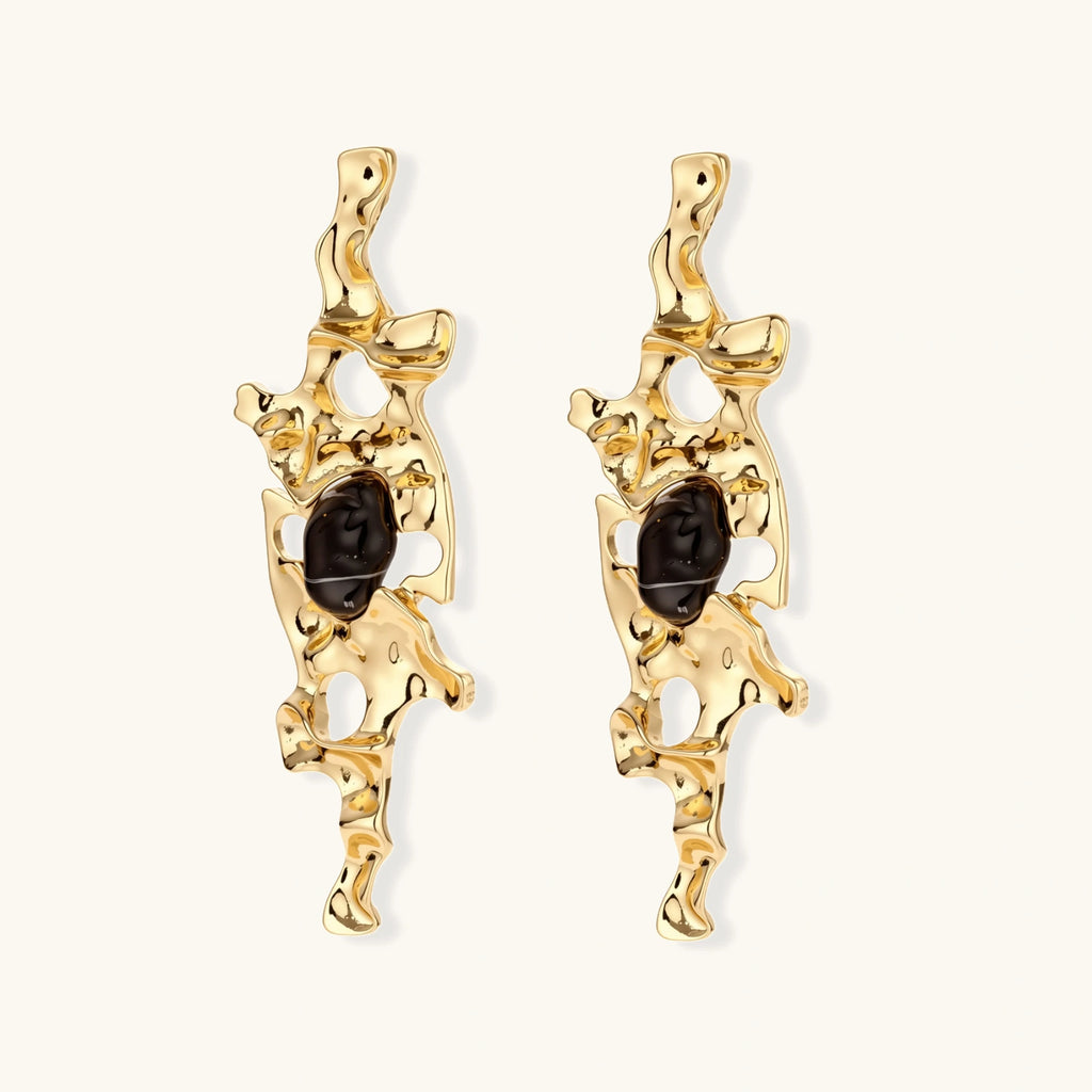 Elongated sculptural earrings with organic openwork design in eco-zinc alloy and dark resin accents on white background.