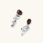 Abstract sculptural silver earrings with brown resin stones featuring organic fluid metalwork design on white background.