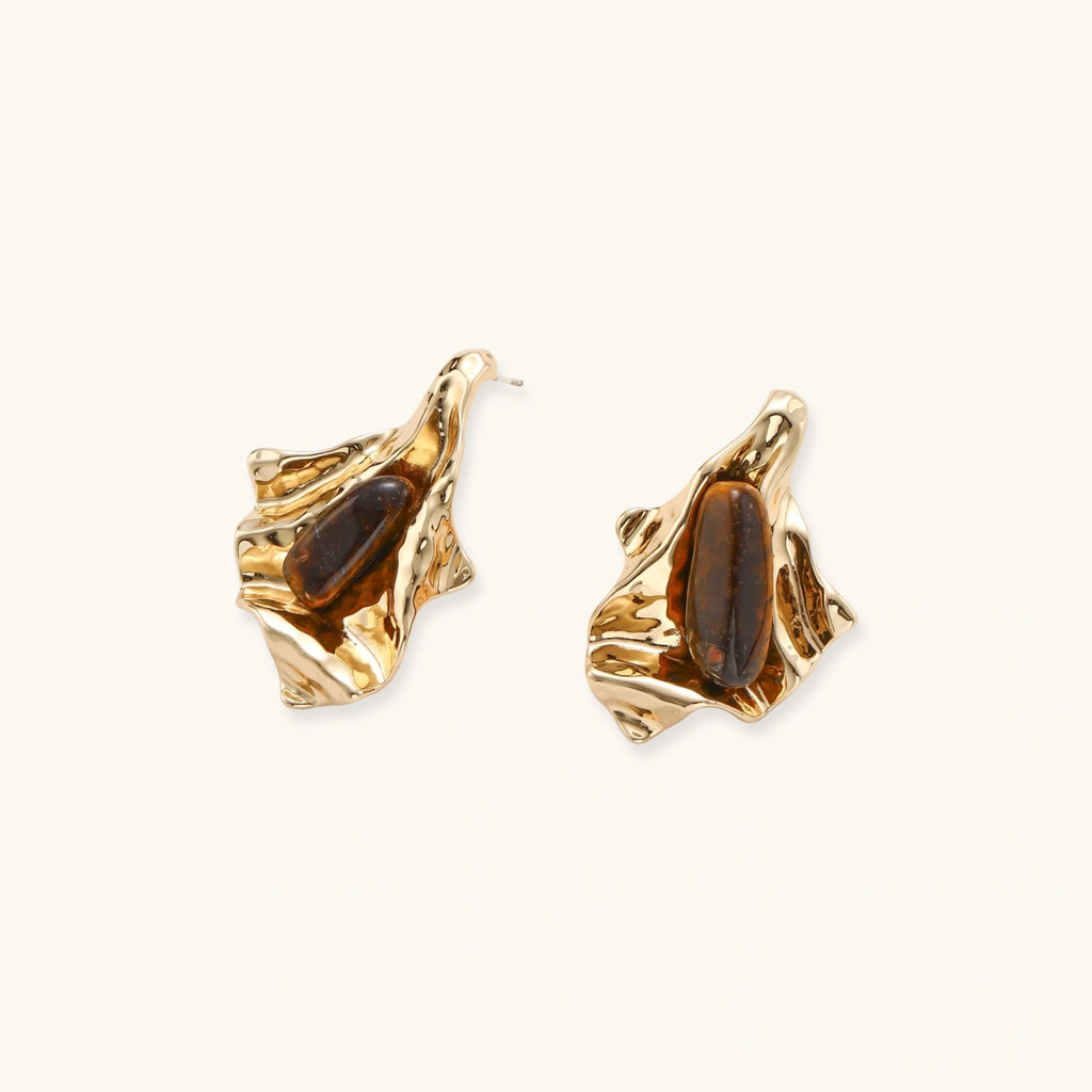 Sculptural stud earrings with organic twisted metal design holding brown gemstones, shown in gold and silver finishes.
