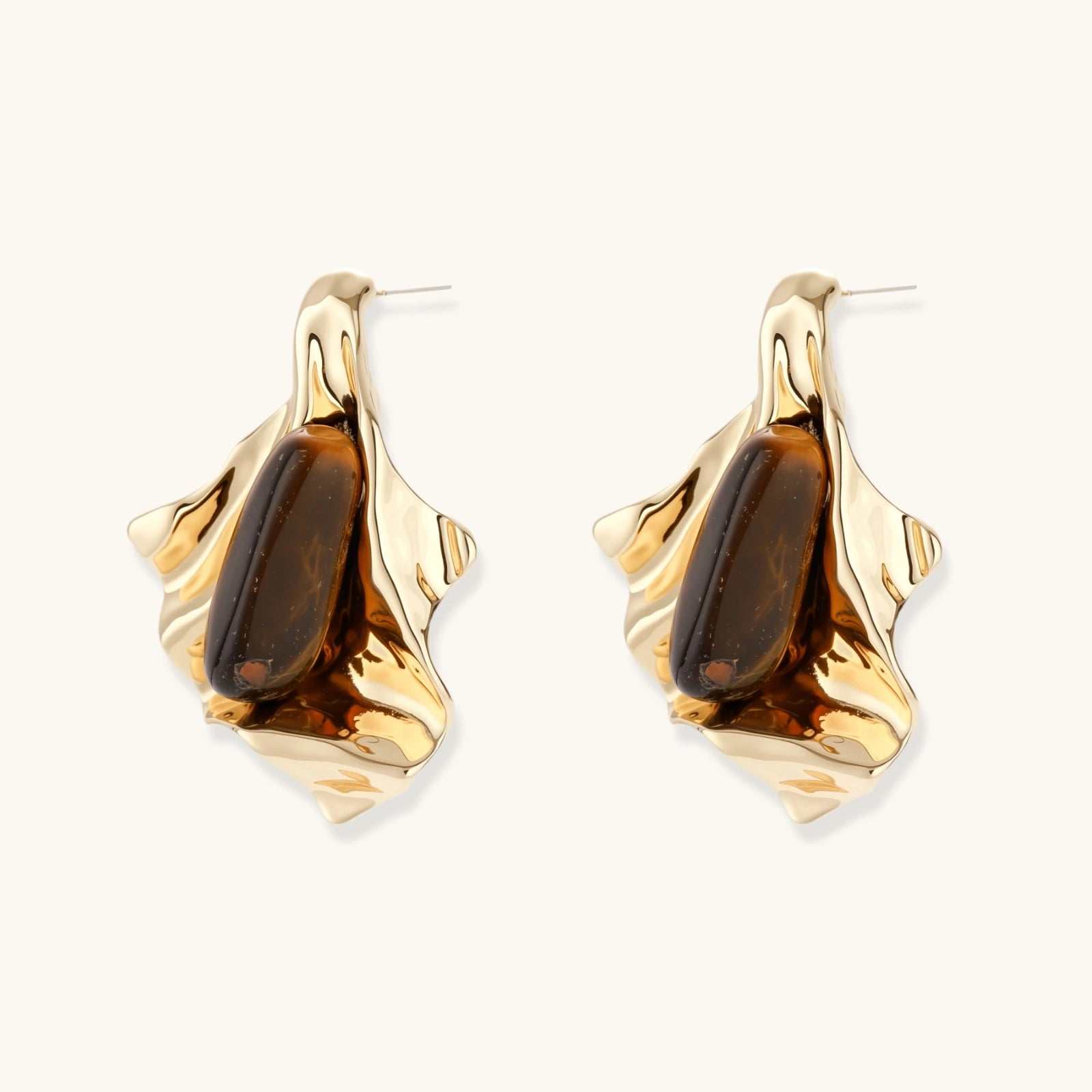Sculptural stud earrings with organic twisted metal design holding brown gemstones, shown in gold and silver finishes.