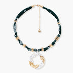 Adjustable necklace with black paisley fabric cord, gold metal spacers, and clear twisted pendant on cream background
