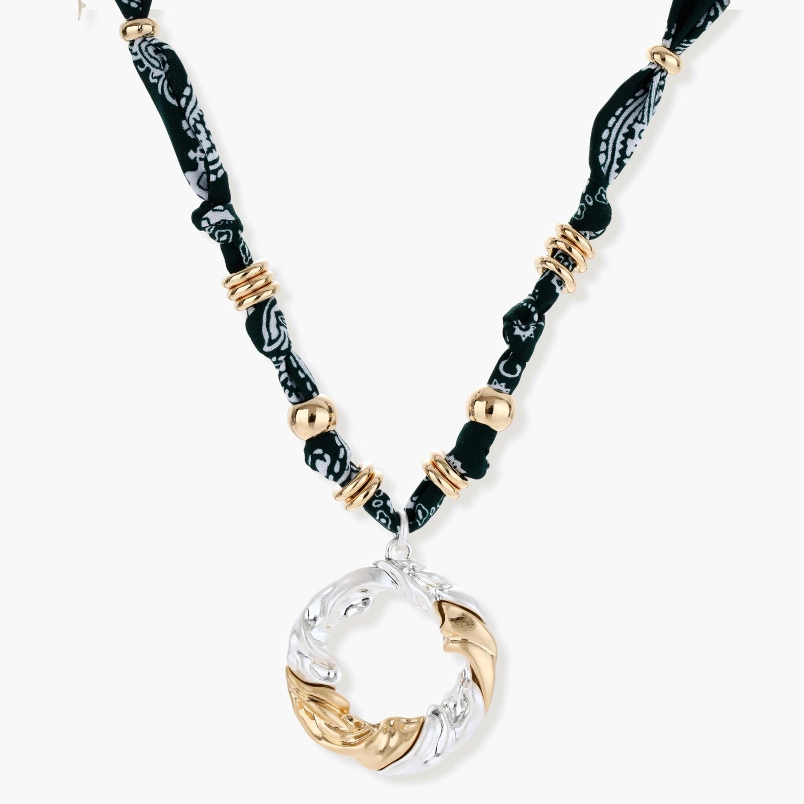 Adjustable necklace with black paisley fabric cord, gold metal spacers, and clear twisted pendant on cream background