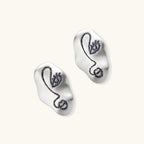 Artistic ear-shaped earrings with minimalist face line art on clear eco-zinc alloy base with sterling silver posts.