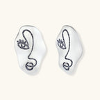 Artistic ear-shaped earrings with minimalist face line art on clear eco-zinc alloy base with sterling silver posts.