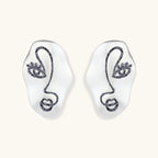 Artistic ear-shaped earrings with minimalist face line art on clear eco-zinc alloy base with sterling silver posts.