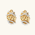 Sculptural rose-shaped stud earrings in gold with silver wire details and S925 posts on cream background.