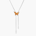 Delicate amber butterfly pendant with zirconia accents and cascading silver-toned chains on adjustable necklace.