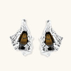 Silver sculptural earrings with flowing molten forms and amber gemstones, featuring 925 silver posts on white background.