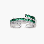 Modern adjustable ring with green baguette stones and clear crystals in parallel bands on white background.